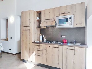 Eine moderne Küche mit Holzschränken, einer Mikrowelle, einem Gasherd und einem Spülbecken.