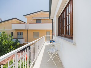A balcony with a white railing, a table with chairs, and a window with blinds. - La Casa di Margot by Interhome (Viareggio)
