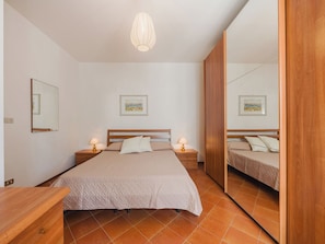 Een slaapkamer met een bed, nachtkastjes, een spiegel en kunst aan de muren.