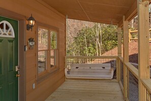 A wooden porch with a green door, a welcome sign, and a bench. - A Beary Special Place | Hot Tub | Game Loft (Sevierville)