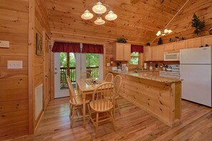 Une cabane en bois dotée d’une cuisine avec un îlot central, des chaises en bois et une table à manger.
