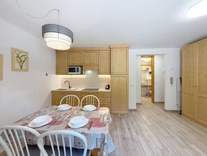 Eine kleine Küche mit Holzschränken, einer Mikrowelle und einem Essbereich mit Tisch für vier Personen.