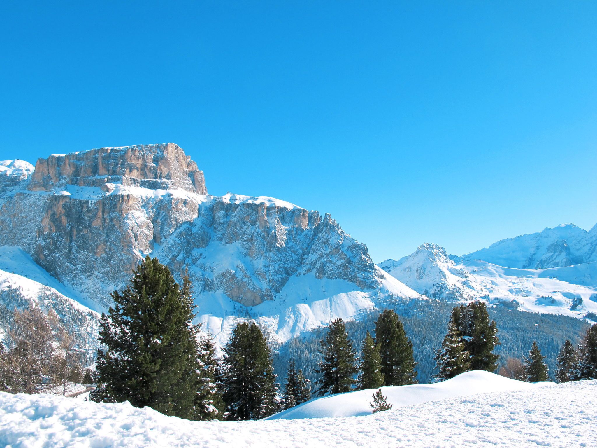 Eine verschneite Berglandschaft mit felsigen Klippen und immergrünen Bäumen.