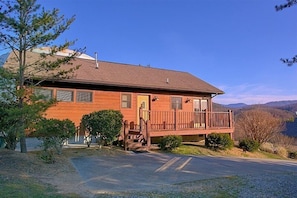 A two-story wooden house with a balcony, a front porch, and a driveway leading to the entrance. - A Dream Come True | Mountain Views | Hot Tub | Fire Pit (Pigeon Forge)