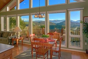 A spacious room with a large dining table, chairs, and a view of mountains through large windows. - A Dream Come True | Mountain Views | Hot Tub | Fire Pit (Pigeon Forge)