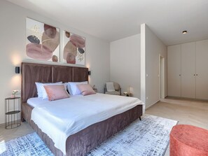 A modern bedroom with a large bed, bedside tables, a chair, and a wardrobe. - Vacation home Riata by Interhome (Poreč)