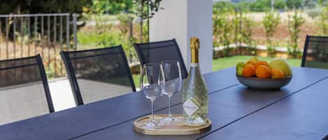 A table with a bottle of Prosecco, two glasses, and a bowl of fruit.