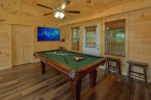 A pool table with balls, a ceiling fan, and a television screen. - A Mountain Palace | Theater Room | Hot Tub (Pigeon Forge)