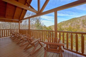 A wooden deck with multiple Adirondack chairs facing a mountainous landscape. - A Rocky Top Ridge | Hot Tub | Game Room (Wears Valley)