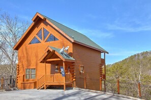 A log cabin with a steep gabled roof, a porch with a bench, and a small balcony. - A Rocky Top Ridge | Hot Tub | Game Room (Wears Valley)