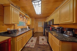 A wooden interior with a kitchen area featuring wooden cabinets, a countertop, a refrigerator, and a microwave. - A Rocky Top Ridge | Hot Tub | Game Room (Wears Valley)