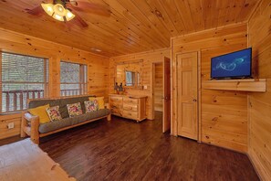 A wooden cabin interior with a sofa, a television, and a wooden dresser. - A Rocky Top Ridge | Hot Tub | Game Room (Wears Valley)