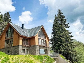 Una casa moderna amb fonaments de pedra, façana de fusta i grans finestres.