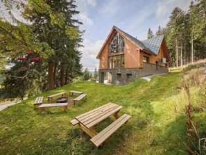 Une maison moderne avec des fondations en pierre, un revêtement extérieur en bois et de grandes fenêtres.