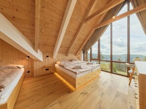 Une pièce aux hauts plafonds, dotée d’un plancher en bois, d’un lit et d’un bureau avec une chaise.