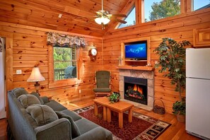 A cozy cabin interior with a fireplace, television, and seating area. - A Romantic Journey | Honeymoon Cabin with Hot Tub (Pigeon Forge)