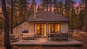 Een chalet met een terras, een open haard en een eethoek.
