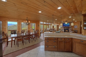A spacious kitchen with a large island, wooden cabinetry, and a fireplace. - A Spectacular View to Remember | Mountain Views | Hot Tub (Gatlinburg)
