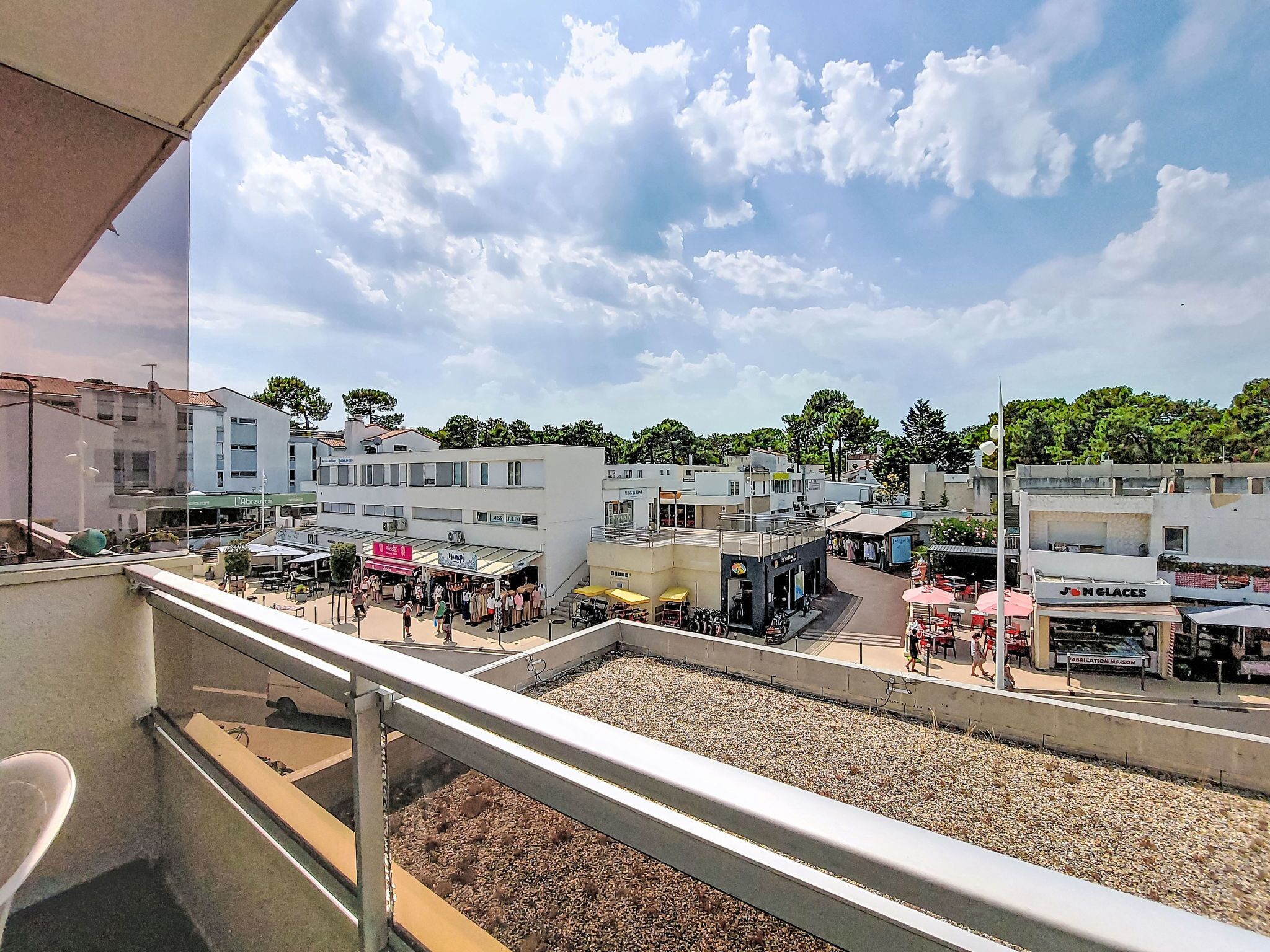 A balcony with a view of a busy street with shops and pedestrians.