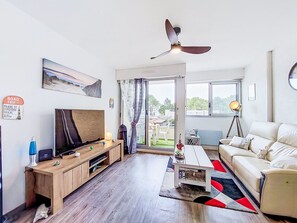 Ein modernes Wohnzimmer mit Flachbildfernseher, Holz-Entertainment-Möbel und Deckenventilator.