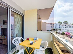 Ein Balkon mit einem gelben Tisch, weißen Stühlen und Blick auf die Stadtlandschaft.