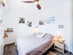 Ein Schlafzimmer mit Bett, Nachttisch, Lampe, Deckenventilator und Wandbildern.