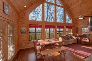 Ein Holzblockhaus-Innenraum mit Esstisch, Bänken, einer Couch und einem Sessel.