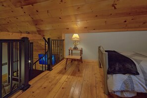 A wooden interior with a bed, a nightstand, and a lamp. - Absolute Heaven Cabin Rental (Wears Valley)