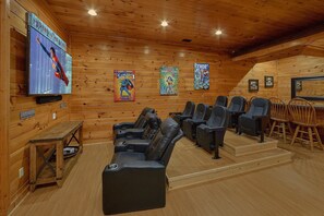 A cozy room with a wooden interior, a flat-screen TV, and a row of black leather chairs. - Absolutely Viewtiful Cabin Rental (Sevierville)