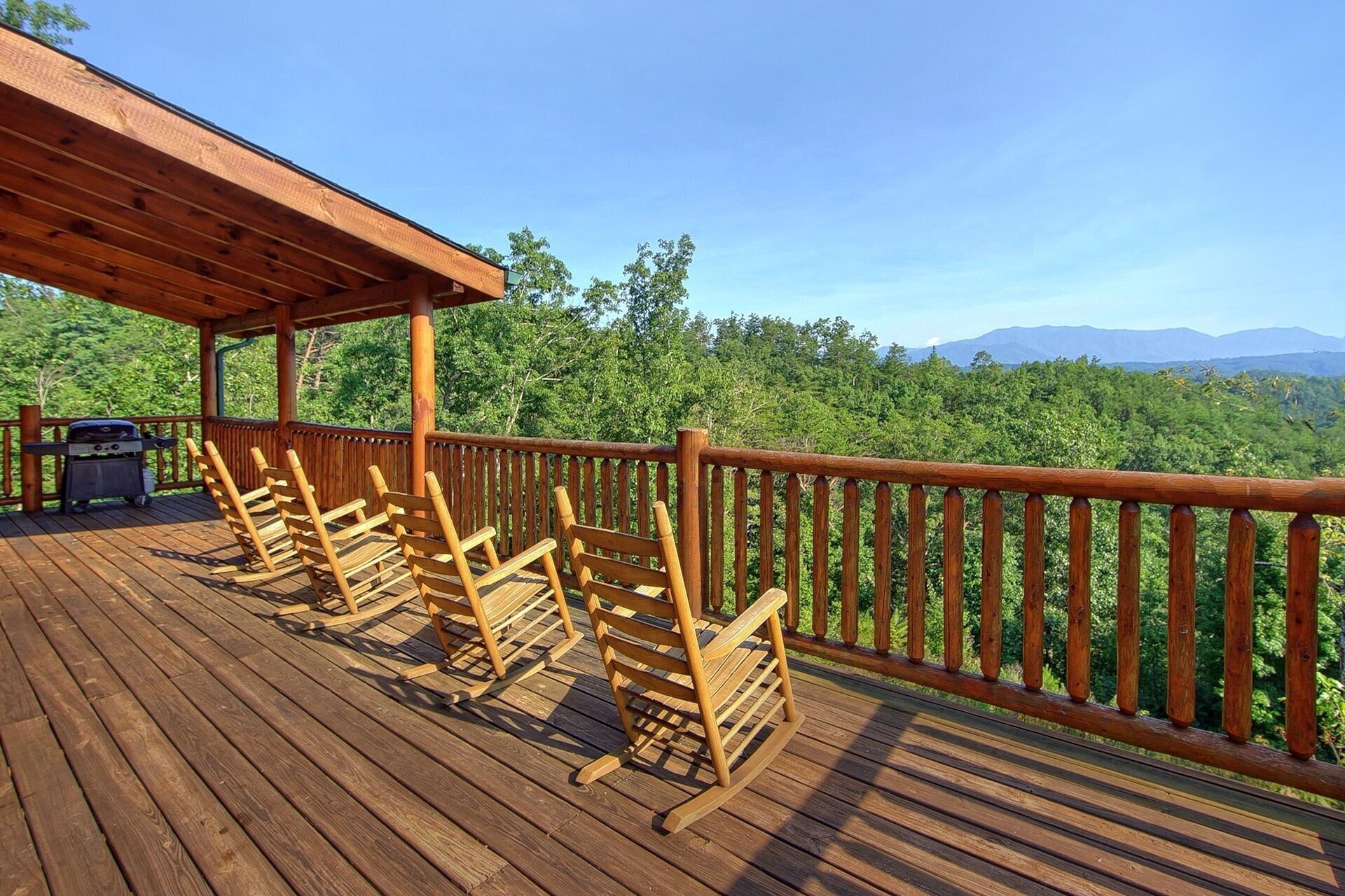 A wooden deck with a covered area and a view of a forested landscape.