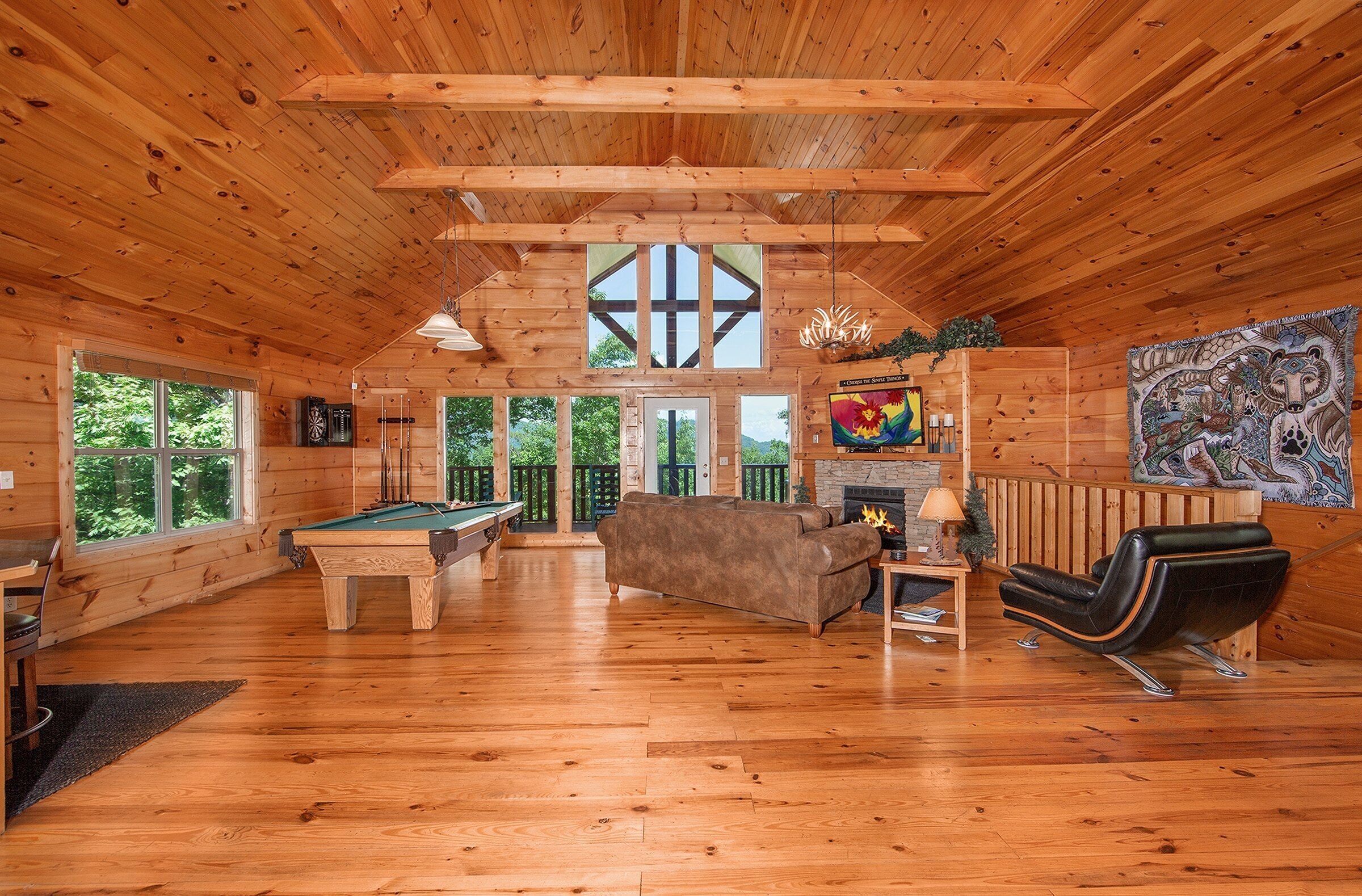 Interior de madera con mesa de billar, sofá y chimenea.