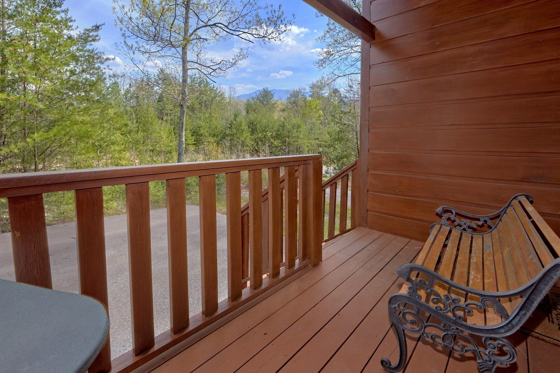 A wooden deck with a bench and a table, overlooking a forested area.