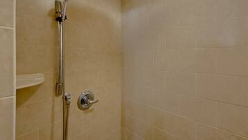 A shower with a handheld showerhead and a wall-mounted control valve.