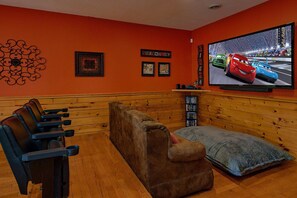 A cozy room with a large flat-screen TV, wooden paneling, and a seating area with multiple chairs. - Almost Heaven Cabin Rental (Pigeon Forge)