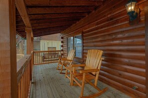 A wooden cabin with a porch featuring rocking chairs and a lantern. - Almost Heaven Cabin Rental (Pigeon Forge)