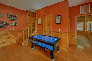 A pool table in a room with wooden paneling, a staircase, and a clock on the wall. - Almost Heaven Cabin Rental (Pigeon Forge)