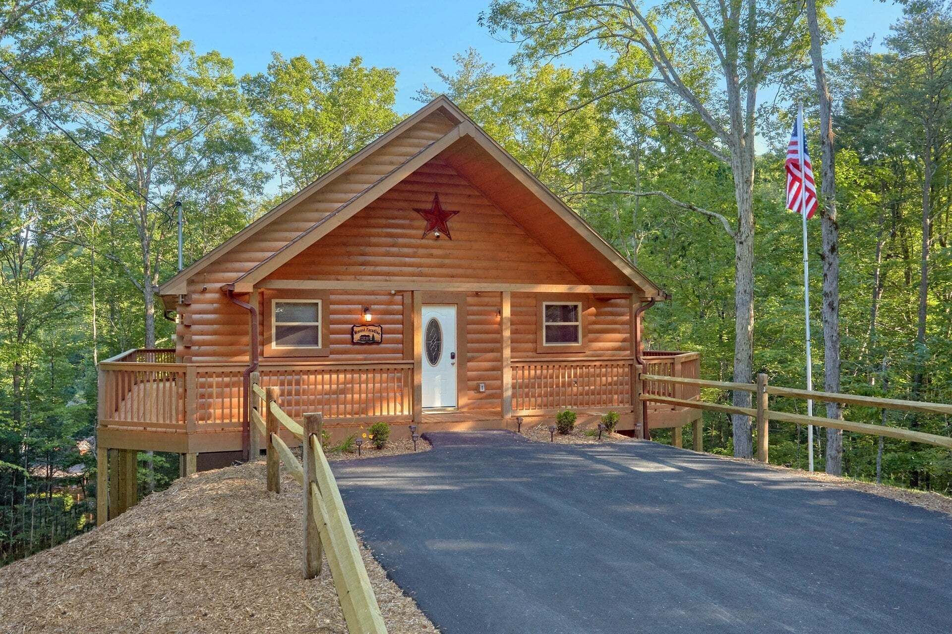 A wooden cabin with a porch, a flag, and a sign indicating it is a 'Welcome to Paradise' property.