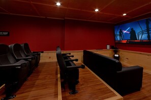 Ein Kino mit Holzböden, roten Wänden und schwarzen Sitzen.