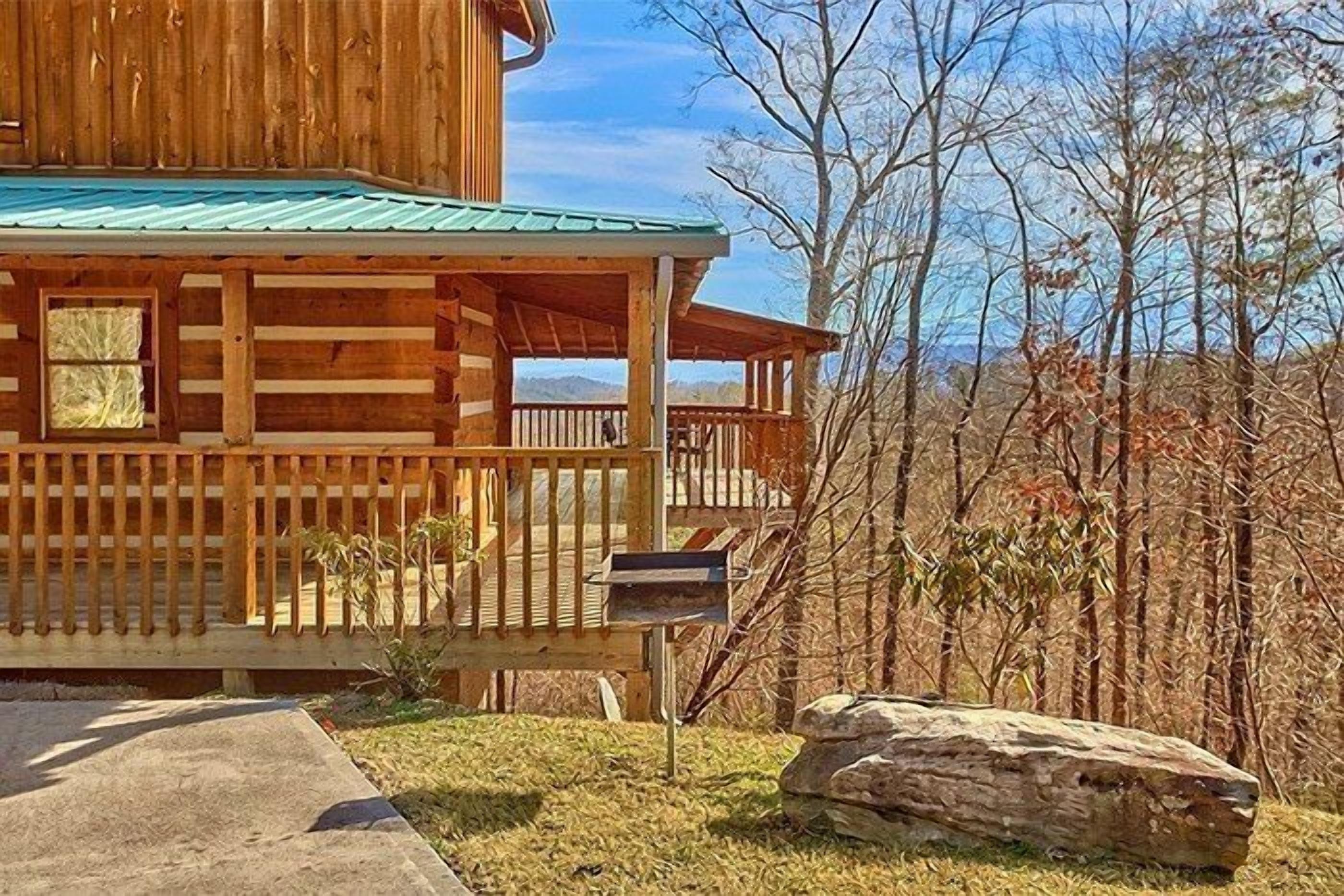 Une cabane en bois avec un porche, une boîte aux lettres et un grand rocher devant.