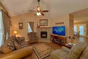 A living room with a fireplace, a television, and a ceiling fan. - Amazing Grace II Vacation Home (Pigeon Forge)