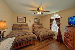A bedroom with two beds, a ceiling fan, a television, and a dresser. - Amazing Grace II Vacation Home (Pigeon Forge)