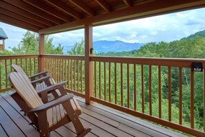A wooden deck with Adirondack chairs overlooking a forested mountain range. - Amazing Views to Remember Cabin Rental (Gatlinburg)