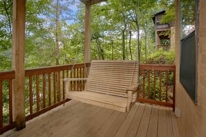 A wooden deck with a bench, surrounded by trees. - Angel's Ridge Cabin Rental (Pigeon Forge)