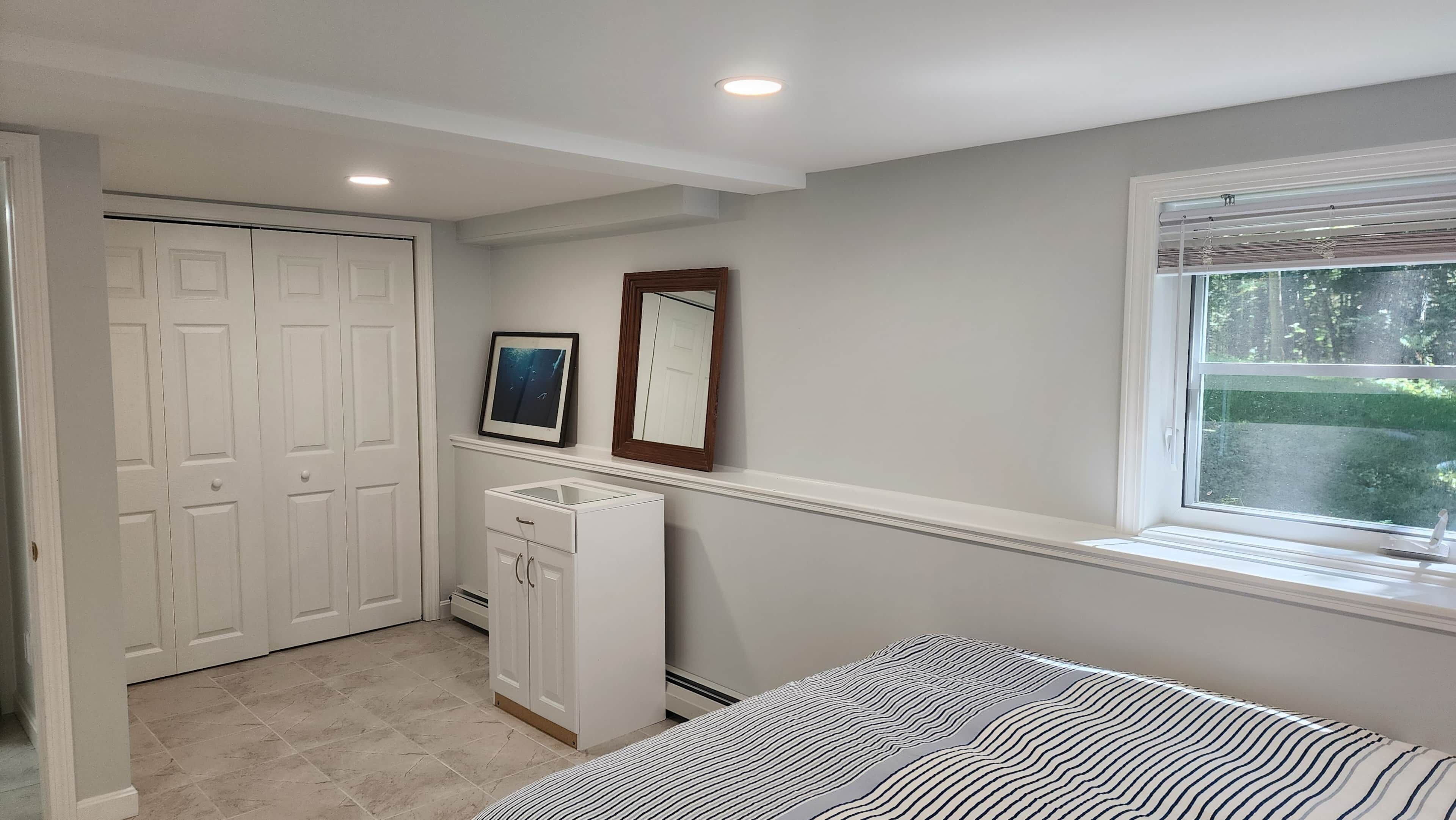 A bedroom with a bed, a dresser, a closet, and a window.