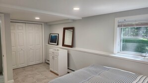 A bedroom with a bed, a dresser, a closet, and a window.