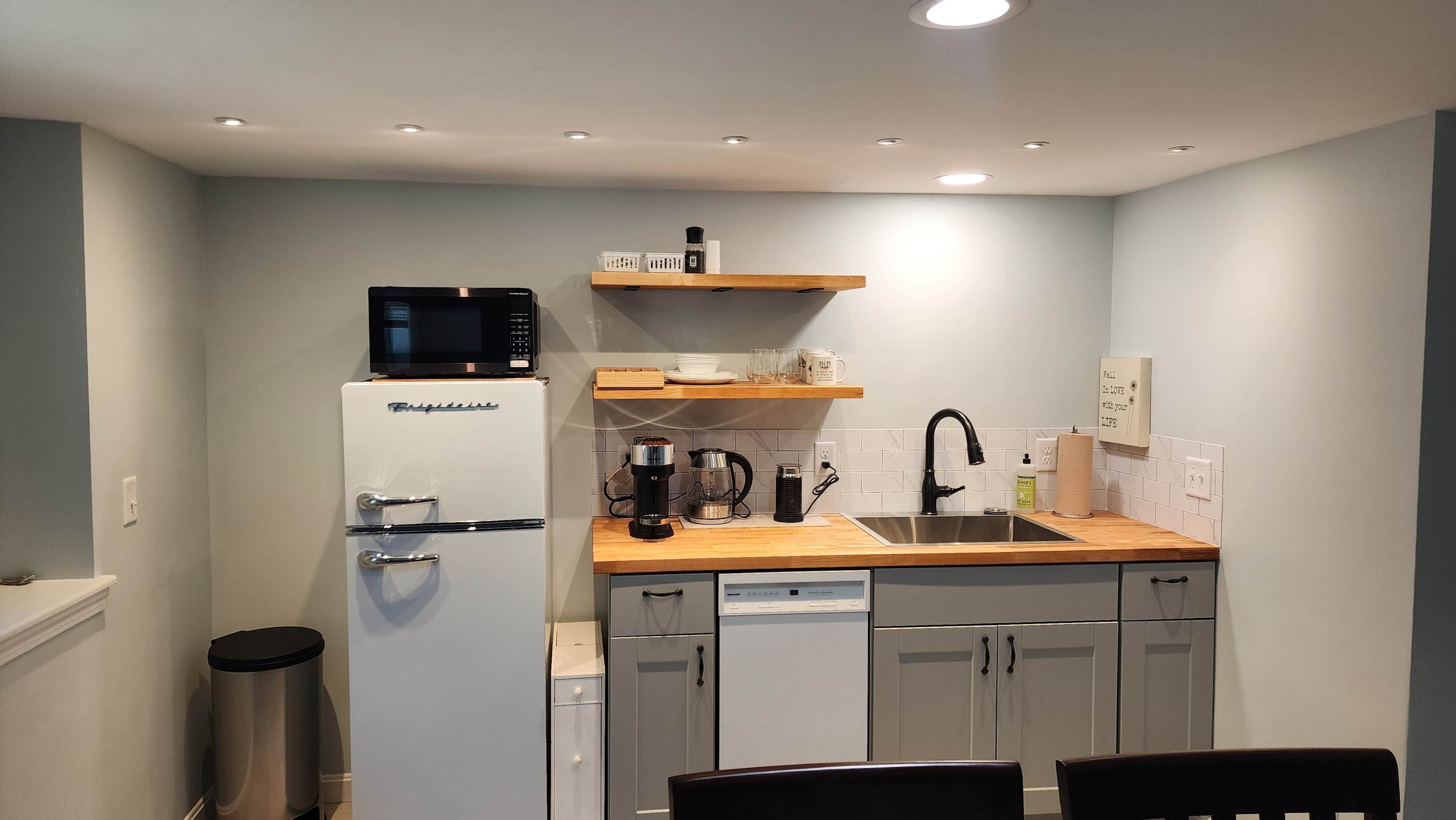 A compact kitchen with a refrigerator, microwave, coffee maker, and a sink.