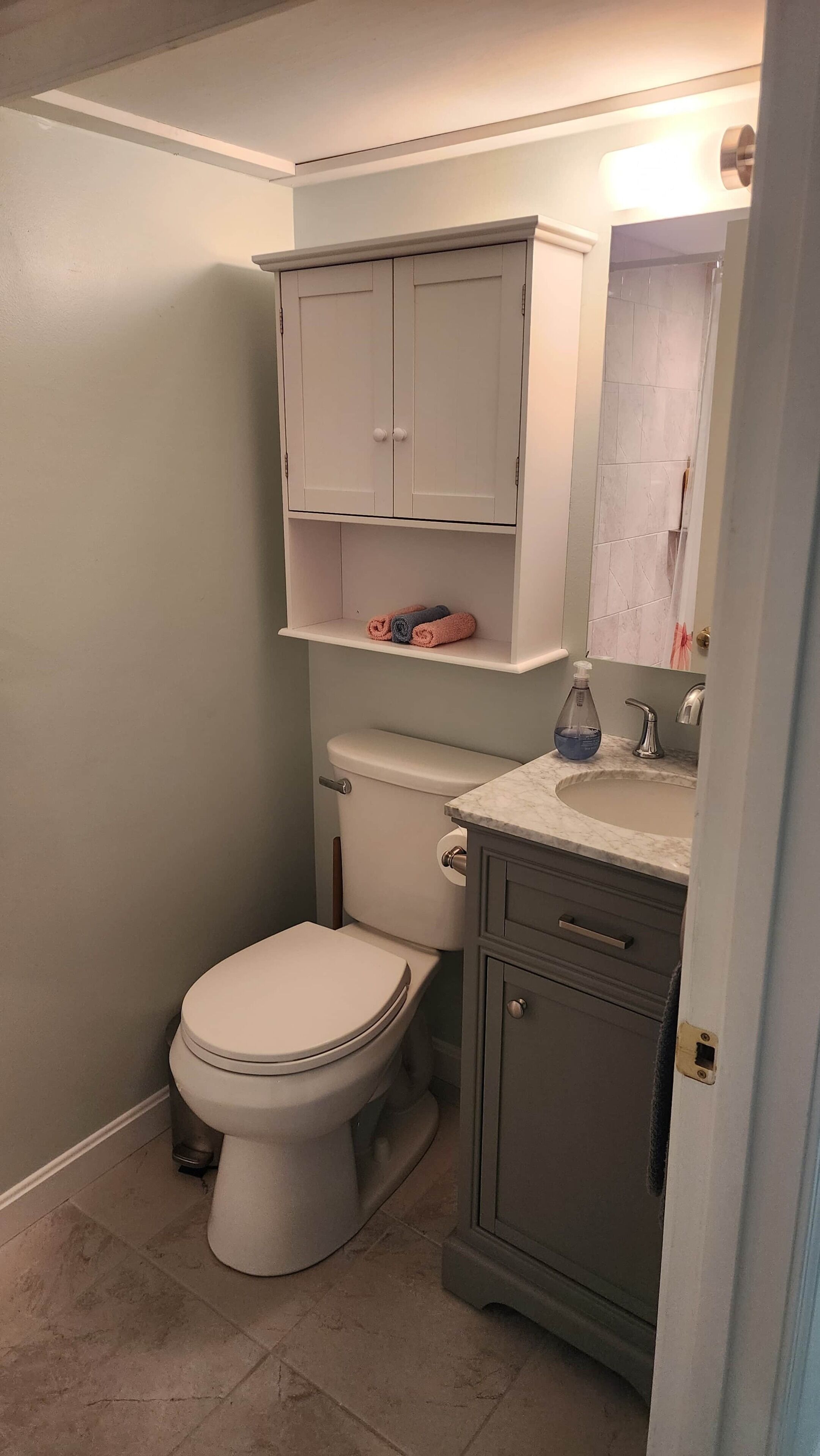 Ein Badezimmer mit Toilette, Waschbecken, Spiegel und Schrank.