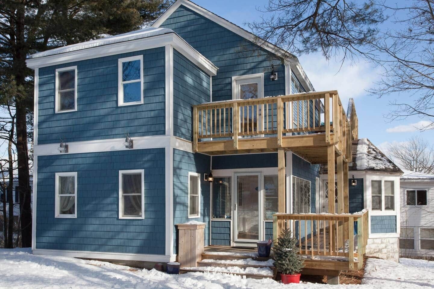 A two-story house with a wooden deck and a small porch.