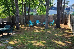 Ein Garten mit Holzzaun, Grill und Gartenmöbeln.