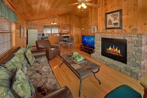 Ein gemütliches Cabin-Interieur mit Kamin aus Stein, Ledermöbeln und einem Fernseher.